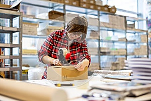 Female Worker Taping Cardboard Box 